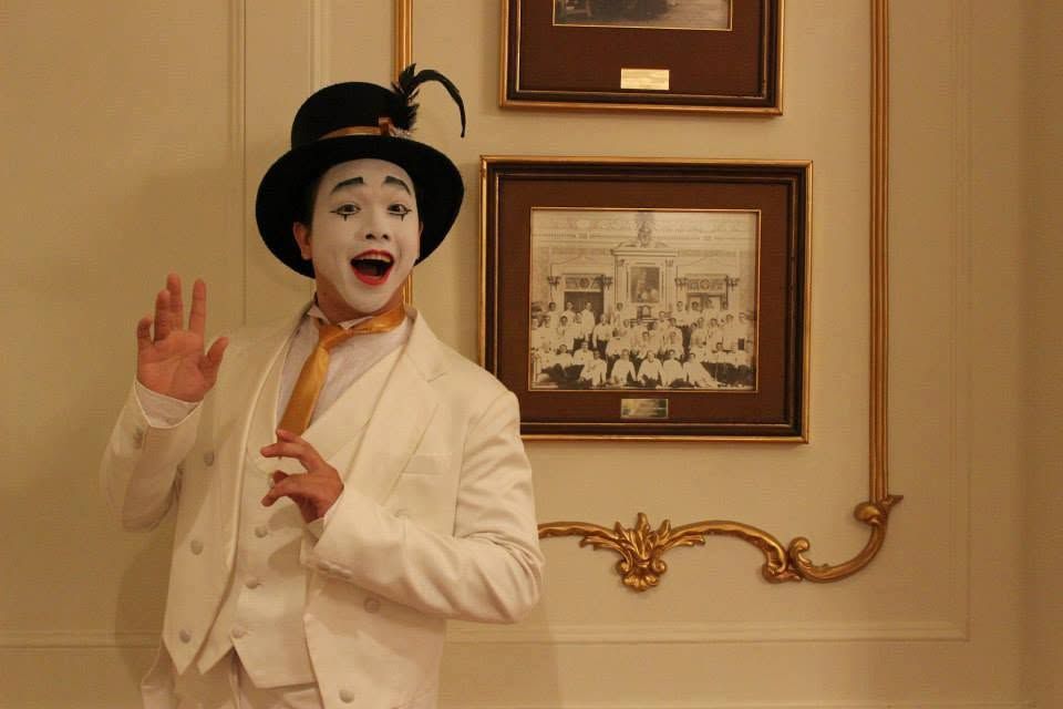 Wasu in white-face mime make-up and a top hat
